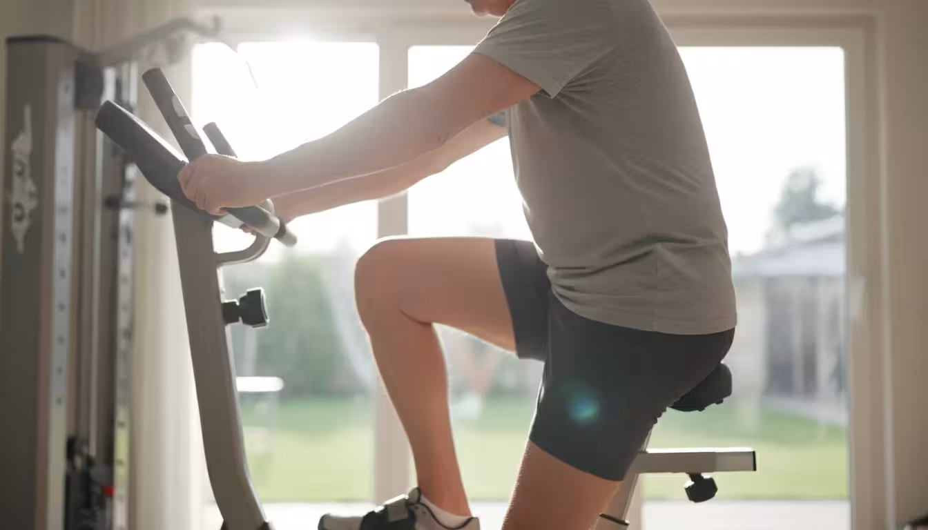 Side view of an older man on a stationary bike, showing a slight, healthy bend in his knee while pedaling.
